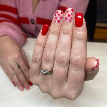 Red nails with tiny heart details on a pink base